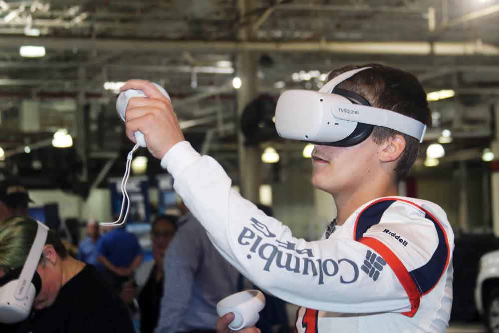 Click to enlarge,  Alex Touchard takes his first adventure into virtual reality with a simulation developed by Transfr to help prepare workers to perform an automobile oil change. This was one of the exhibits at the Central Carolina Community College Manufacturing Day event. 